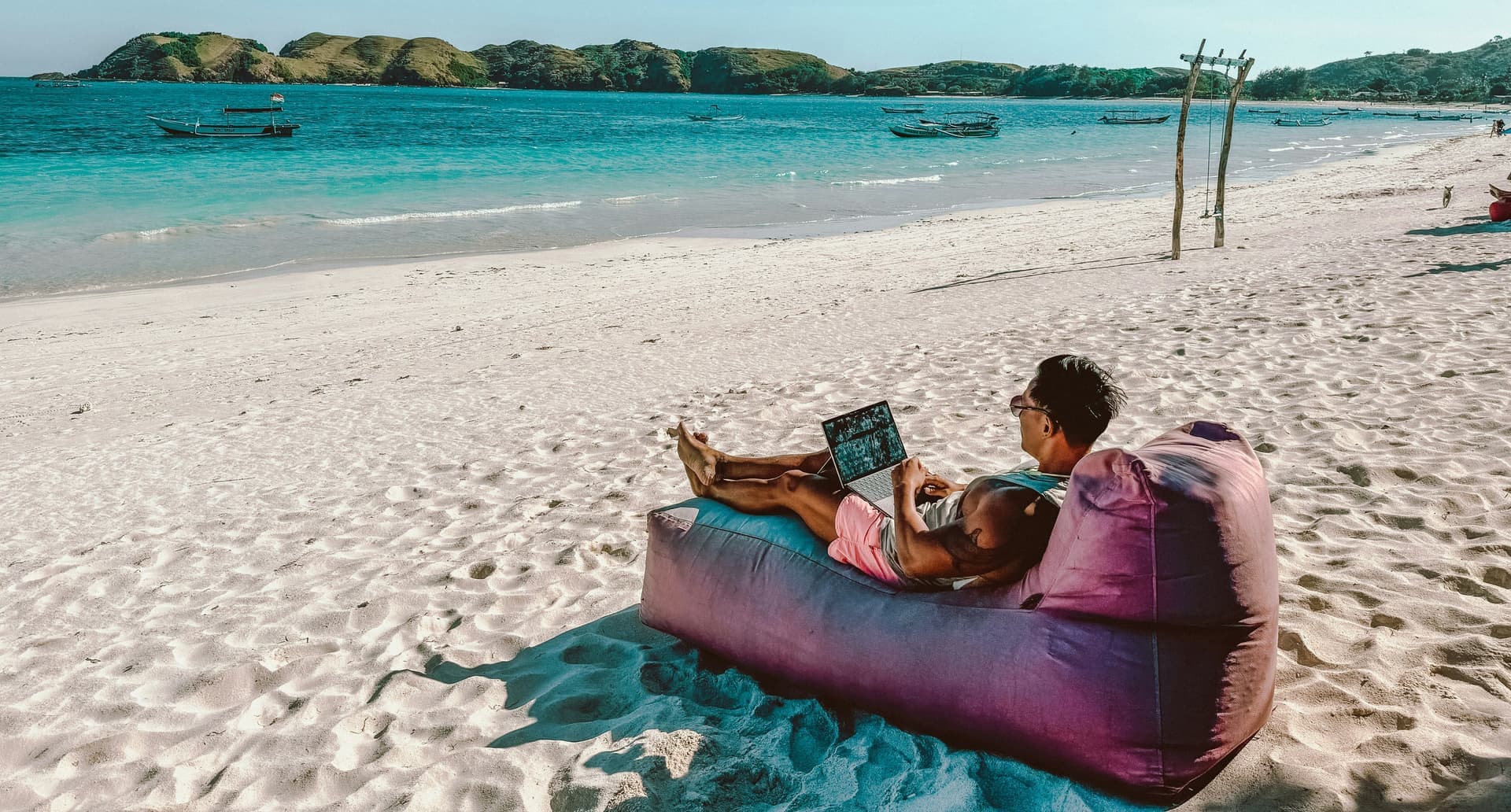 Working from a laptop on a bean bag on a white-sand Bali beach
